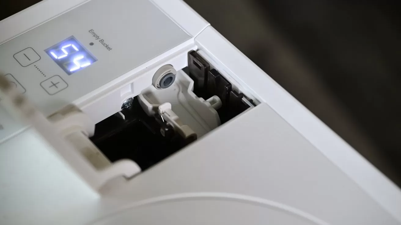 Close-up of a white appliance control panel showing a digital display reading 54 and an open compartment revealing internal plastic components and wiring