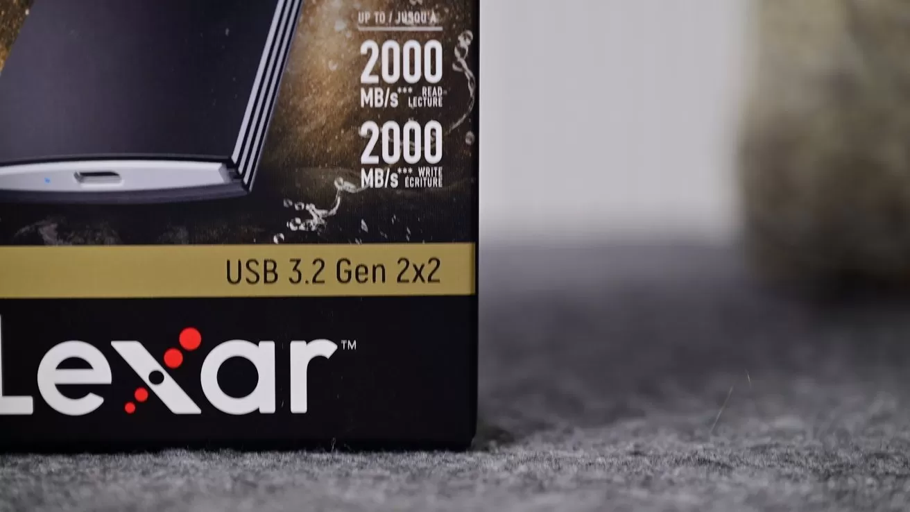 Close-up of Lexar USB 3.2 Gen 2x2 product box on gray surface, showing branding, speed rating of 2000 MB/s read and write, with blurred background