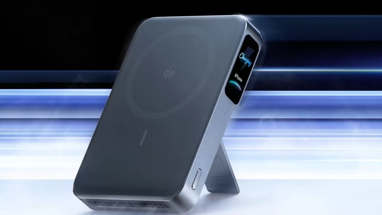 Sleek gray portable device standing on a built-in kickstand, featuring a circular pattern on its front and glowing blue status lights on the side against a blurred futuristic background