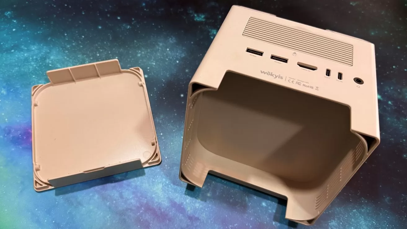 Beige computer case with open back panel showing ports, including USB and HDMI, on a blue and black cosmic background.
