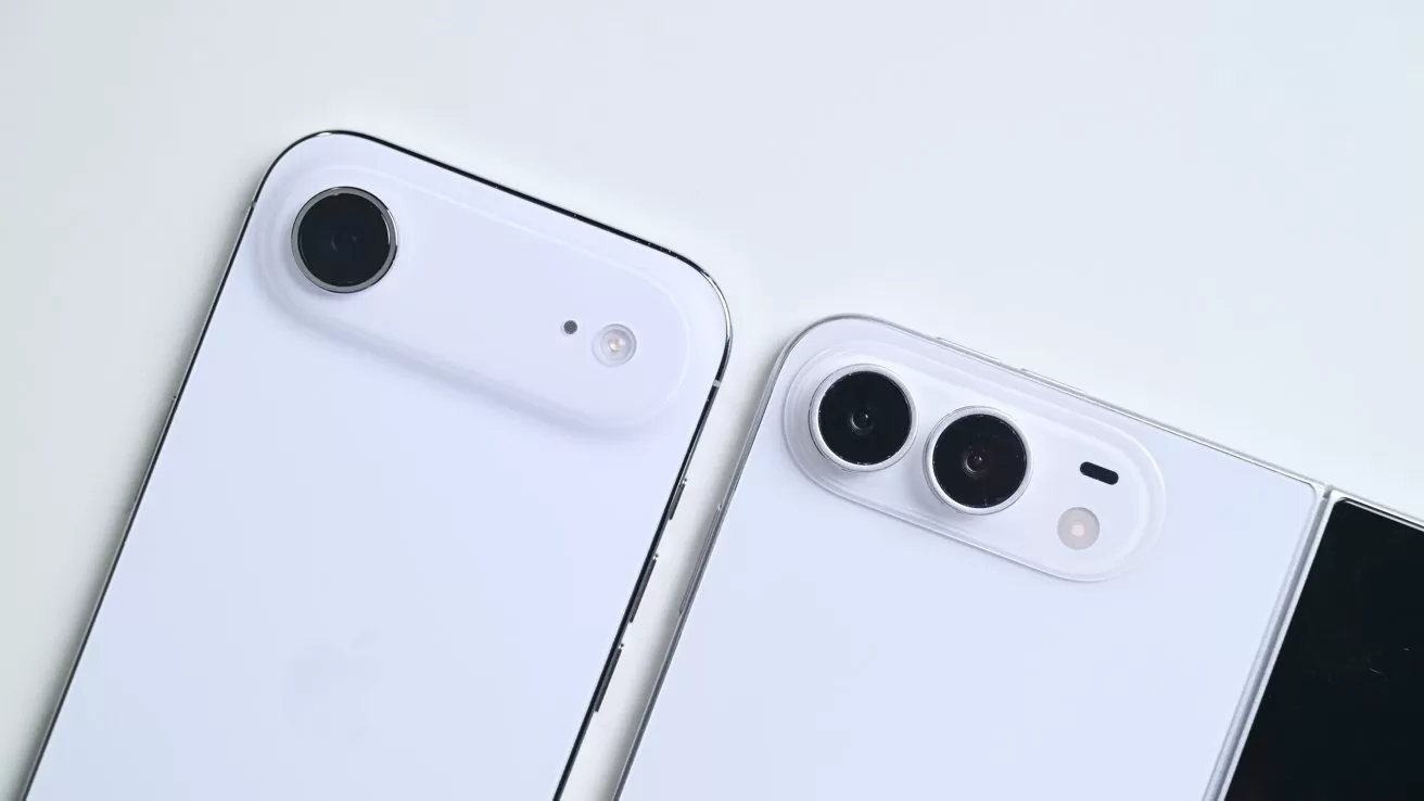 Two white smartphones on a light surface, one with a single rear camera lens, the other with two lenses and a flash, partially showing a black screen edge