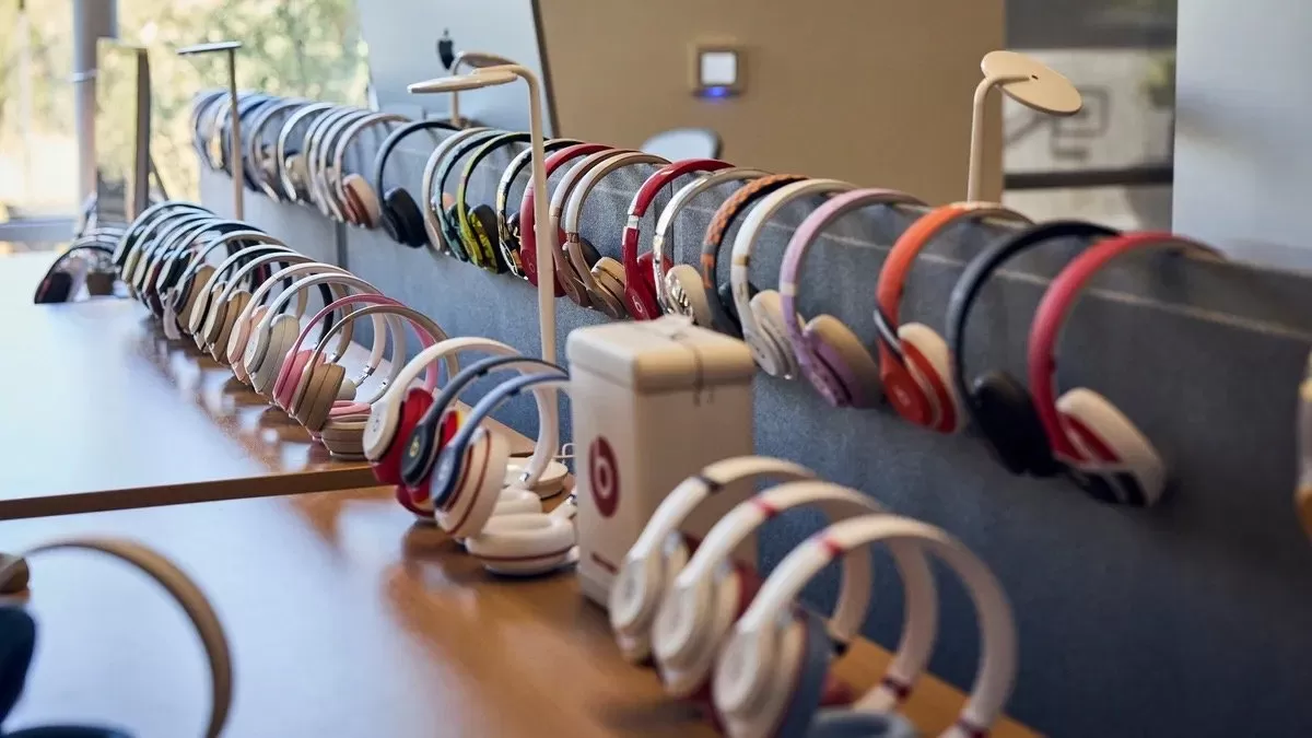 Display table in a modern store holding dozens of colorful headphones arranged neatly on metal rails, with natural light from large windows brightening the background
