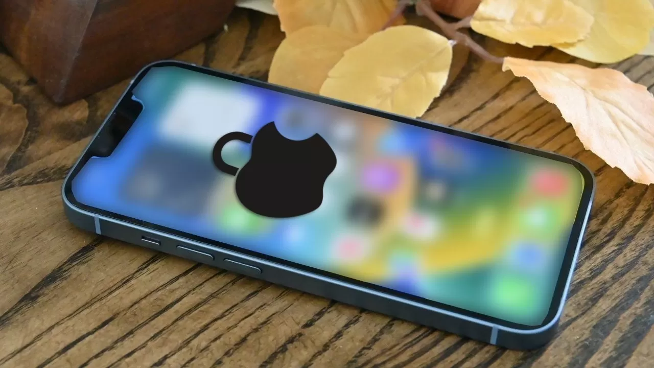Smartphone lying on a wooden table with its colorful screen blurred and a large black Apple logo overlay; autumn leaves and a wooden box are in the background