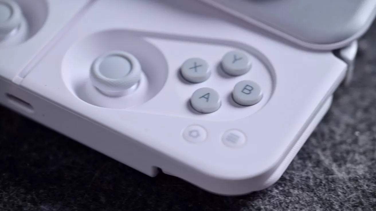 Close-up of a white gaming controller's right side, featuring a joystick and four circular buttons labeled X, Y, A, B on a textured dark surface.