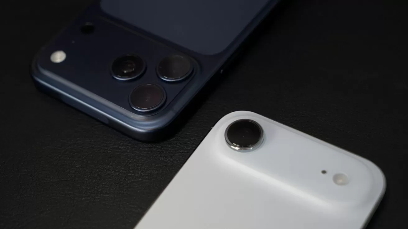 Close-up of two smartphones on a dark surface, one dark blue with three rear cameras and one white with a single rear camera, both showing minimalist modern designs