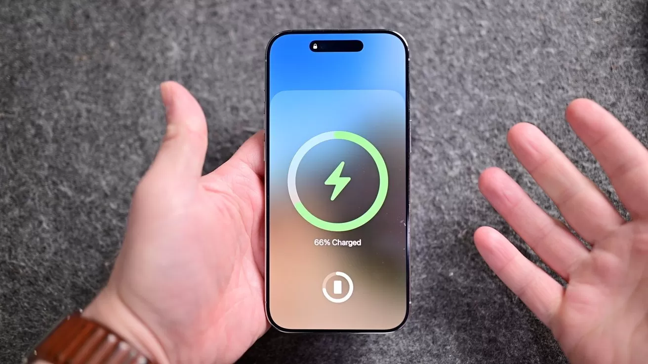 Hand holding a smartphone on a gray surface, screen showing a large green charging circle with lightning bolt and battery status at 80 percent, another hand gesturing nearby