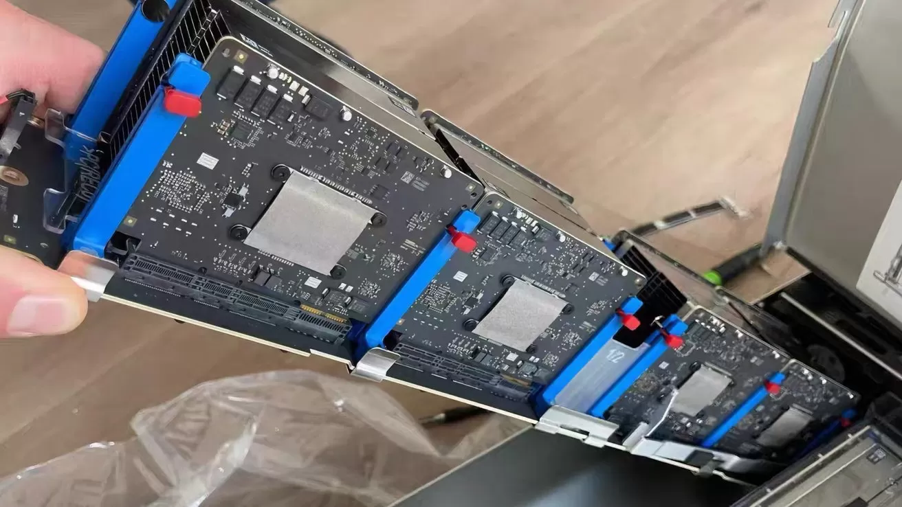 Person holding a row of several computer server blades with exposed circuit boards, aligned vertically inside an open metal chassis on a wooden floor