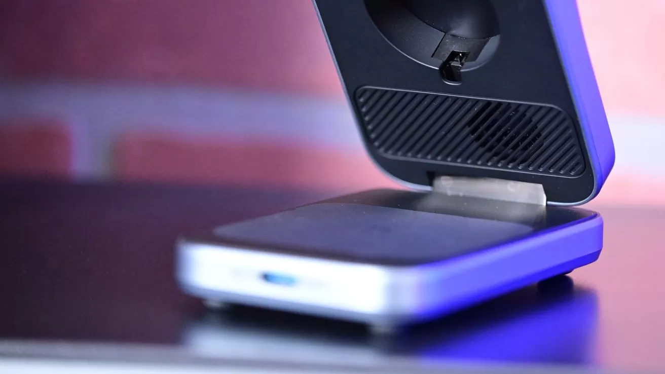 Close-up of a modern electronic card reader or payment terminal on a counter, partially open with a glowing blue light, against a softly blurred background with brick-like pattern