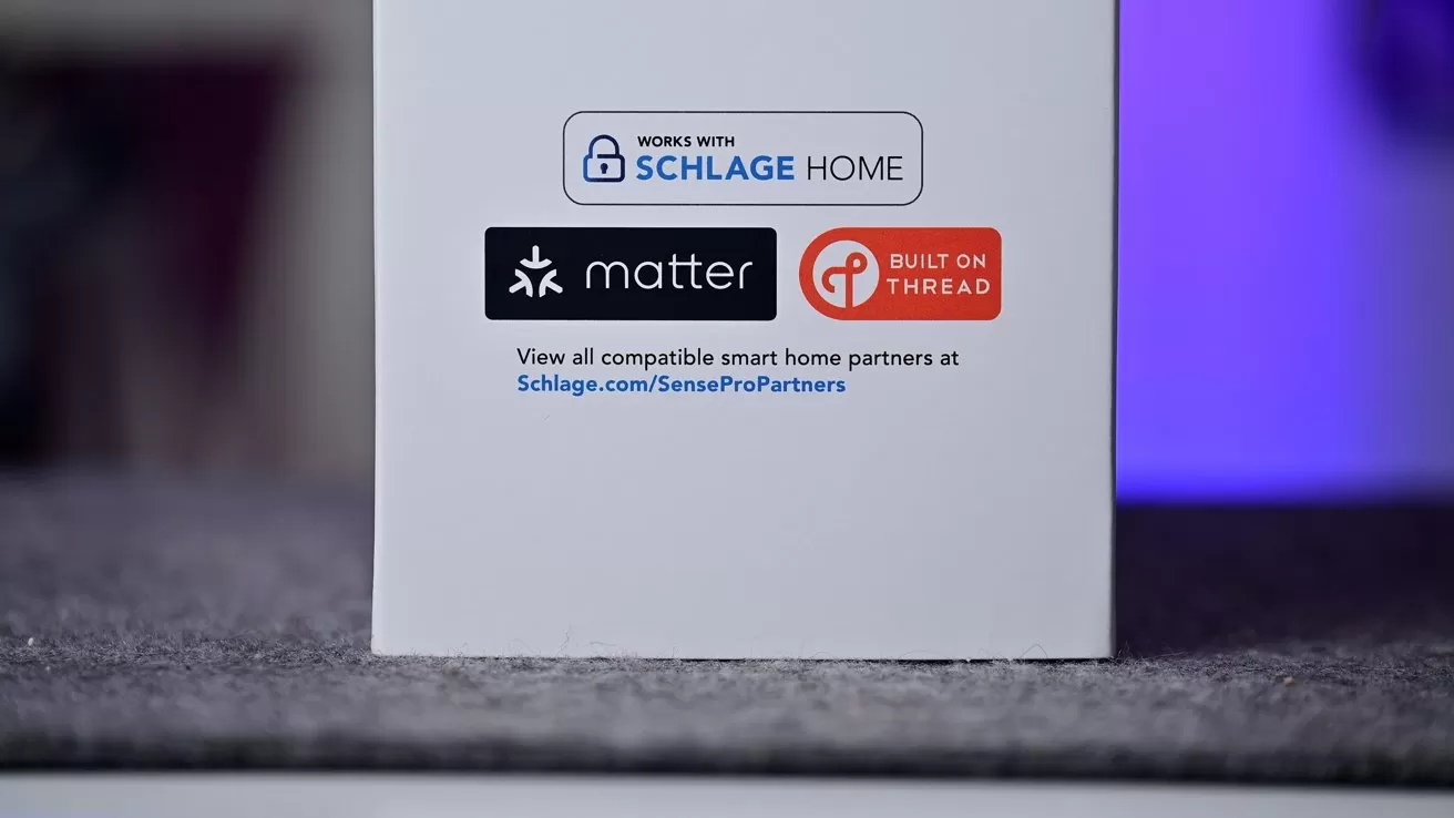 Product box showing compatibility logos for Schlage Home, Matter, and Built on Thread, with small printed text and website link against a white background on a gray surface