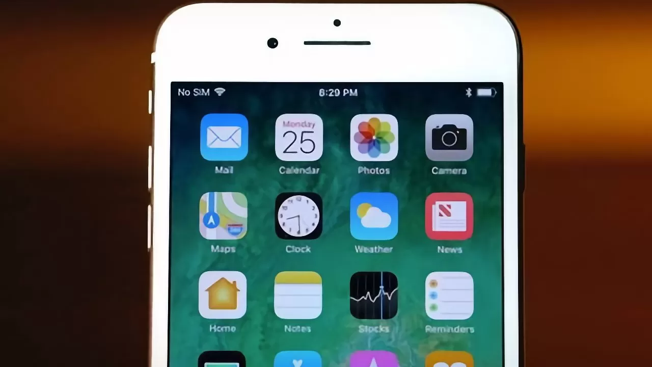 Close-up of an iPhone screen showing home screen icons including Mail, Calendar, Photos, Camera, Maps, Clock, Weather, News, Home, Notes, Stocks, and Reminders against a blurred background