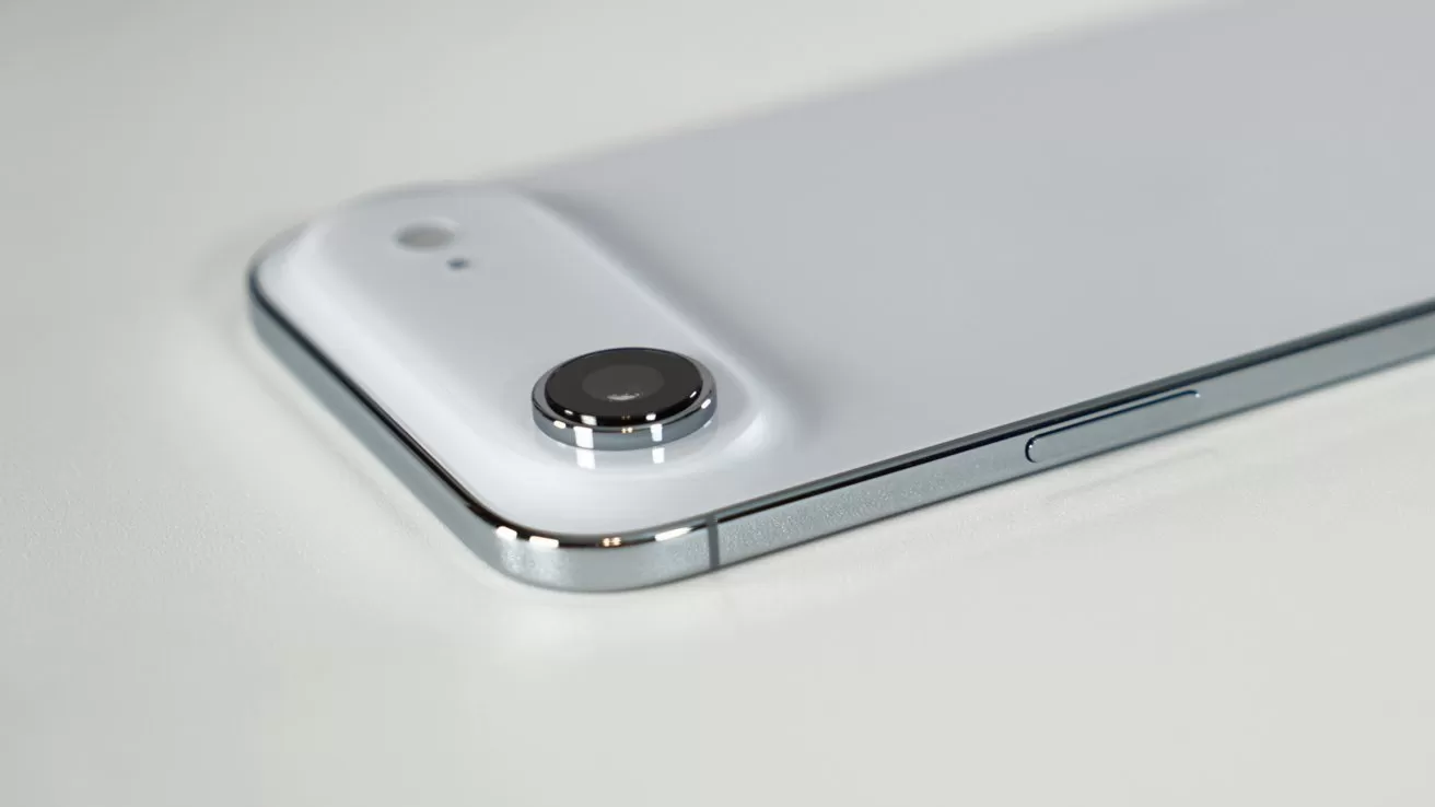 Close-up of a modern white smartphone lying flat, showing a single rear camera with raised lens, small flash, and shiny metallic edge with a side button visible