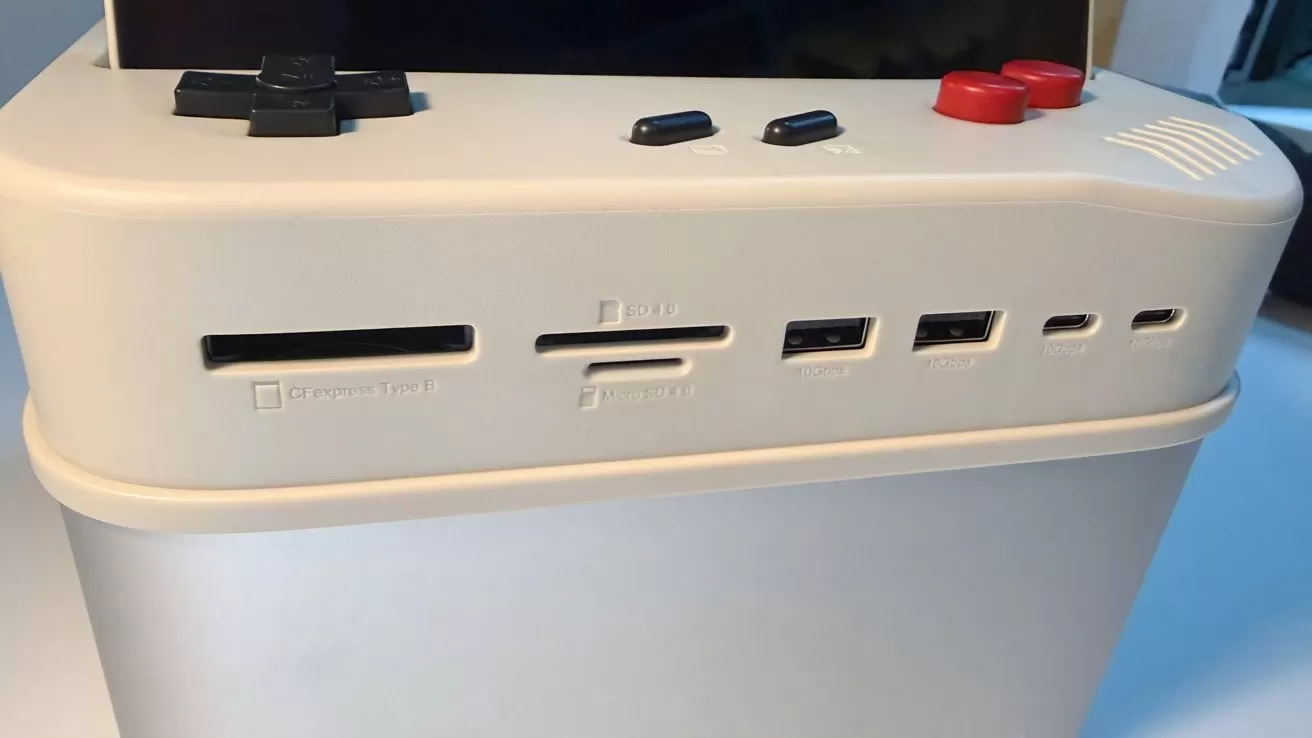 Retro-style gaming console with cream-colored casing, black and red buttons on top, and multiple front ports including SD card slot, USB ports, and small ventilation holes