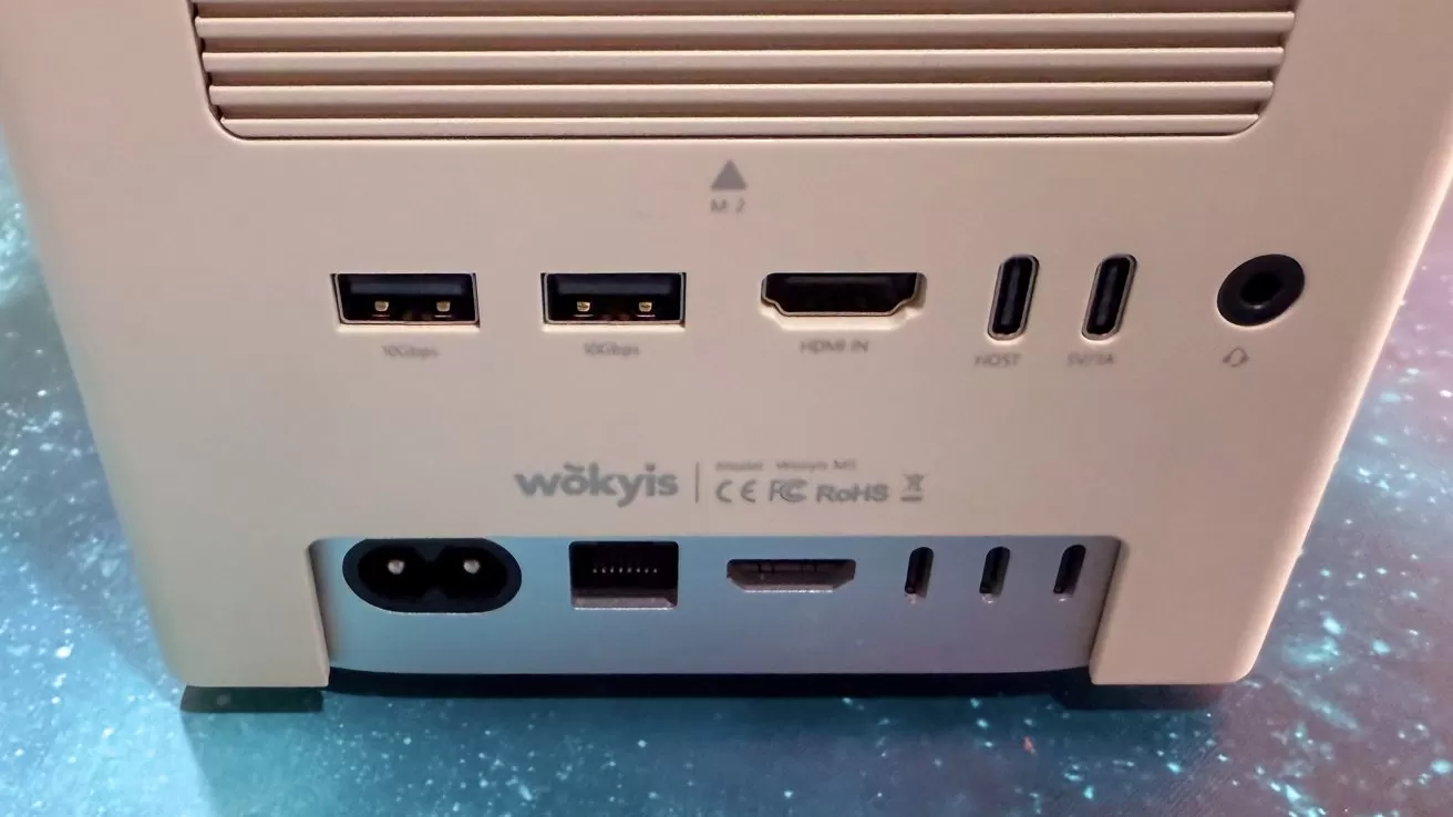 White electronic device with two USB ports, HDMI input, two USB-C ports, power outlet, Ethernet, and additional HDMI and USB-C ports on a starry background.