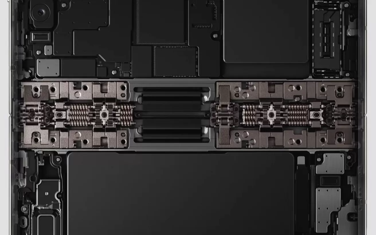 Internal view of a laptop showing symmetrical components, including a central hinge mechanism, battery cells, and circuit boards arranged in a clean, rectangular, industrial layout
