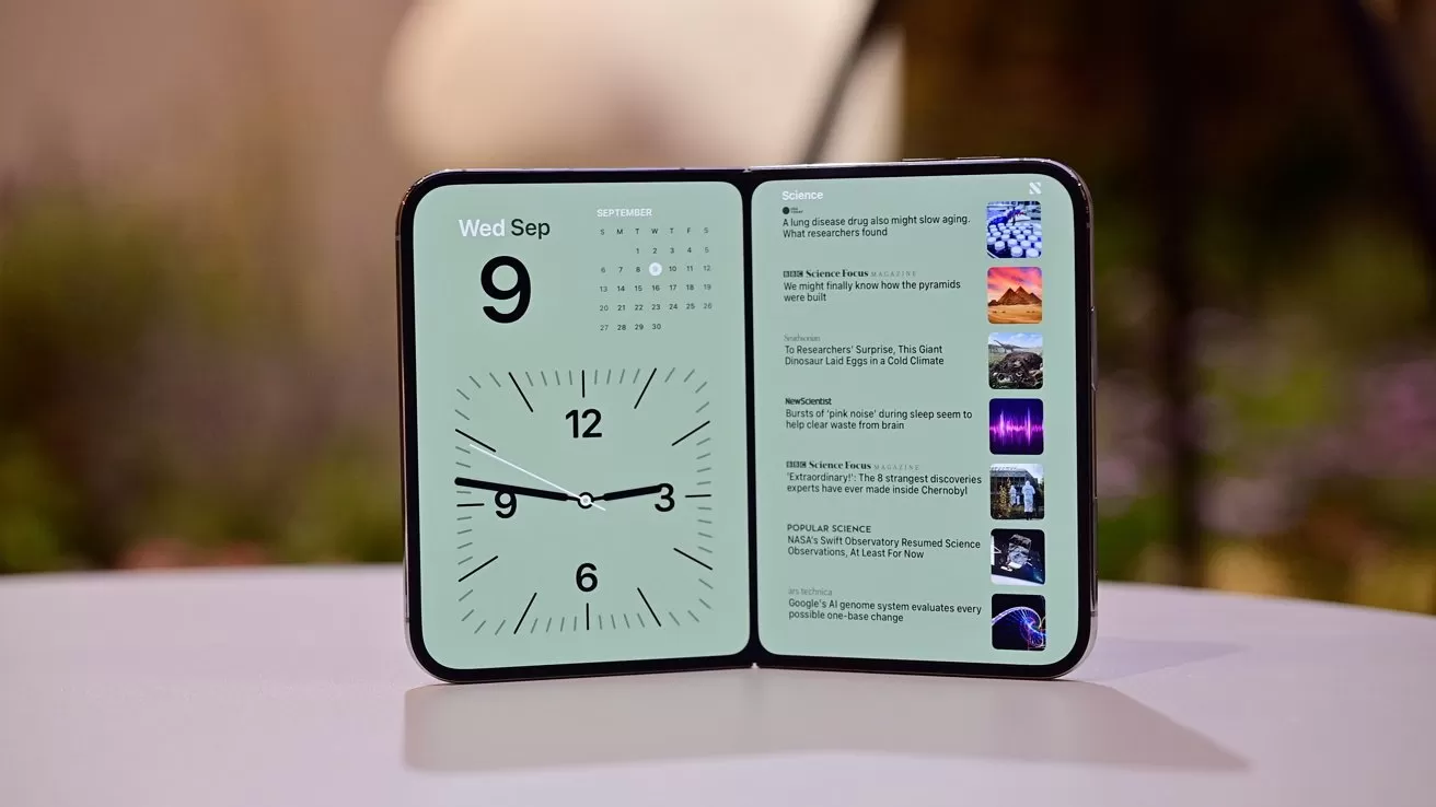 Foldable tablet on a table, left screen showing large analog clock and calendar for Wednesday September 9, right screen displaying a vertical list of colorful news article thumbnails and headlines