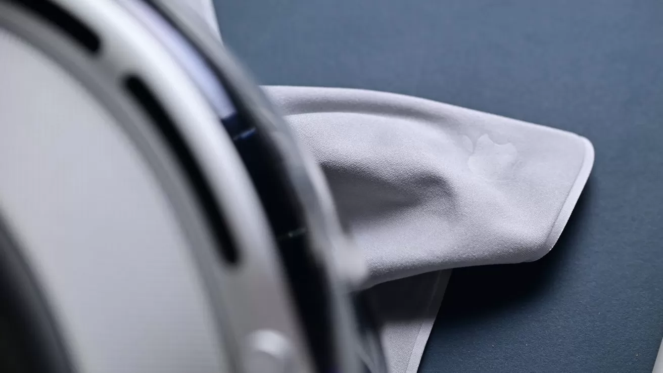 Close-up of a robotic vacuum or floor cleaner with a white microfiber cloth attachment resting on a dark smooth surface, emphasizing the cleaning pad and device edge