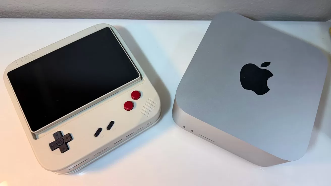 Retro-style handheld gaming device with large screen beside a compact silver Apple Mac mini on a white surface, both viewed from above