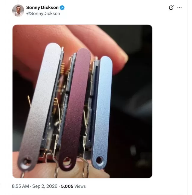 Close-up of a hand holding three slim metal gadget frames in silver, purple, and blue, showing small internal components and screw holes at one end