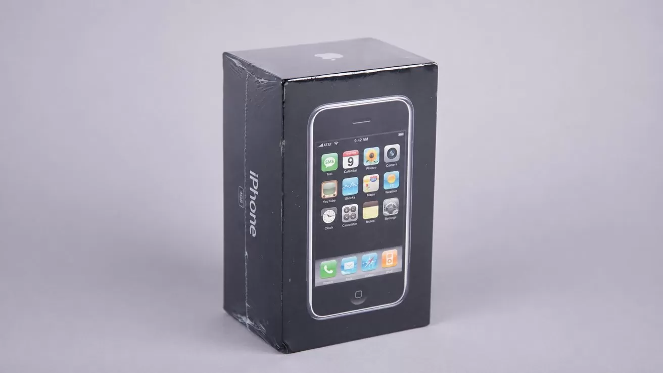 Black retail box standing upright, displaying an early iPhone with classic app icons on the front, against a plain light gray background.