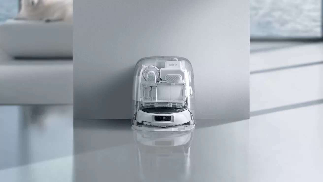 Small futuristic robotic vacuum with a transparent dome sits on a glossy floor in a minimalist, light gray room with soft natural light and blurred furniture in the background