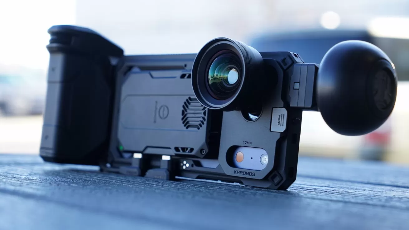 High-end iPhone camera rig lying on a table, featuring a large wide-angle lens, sturdy protective case, ergonomic grip handle, and background blurred by shallow depth of field