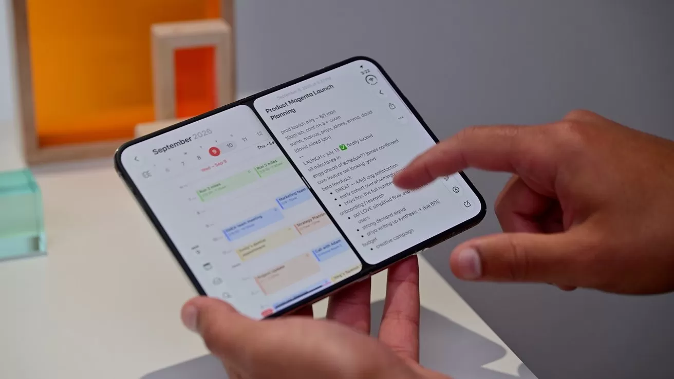 Person holding an open foldable smartphone, displaying a calendar app on the left screen and an email or task list on the right, against a minimal indoor background