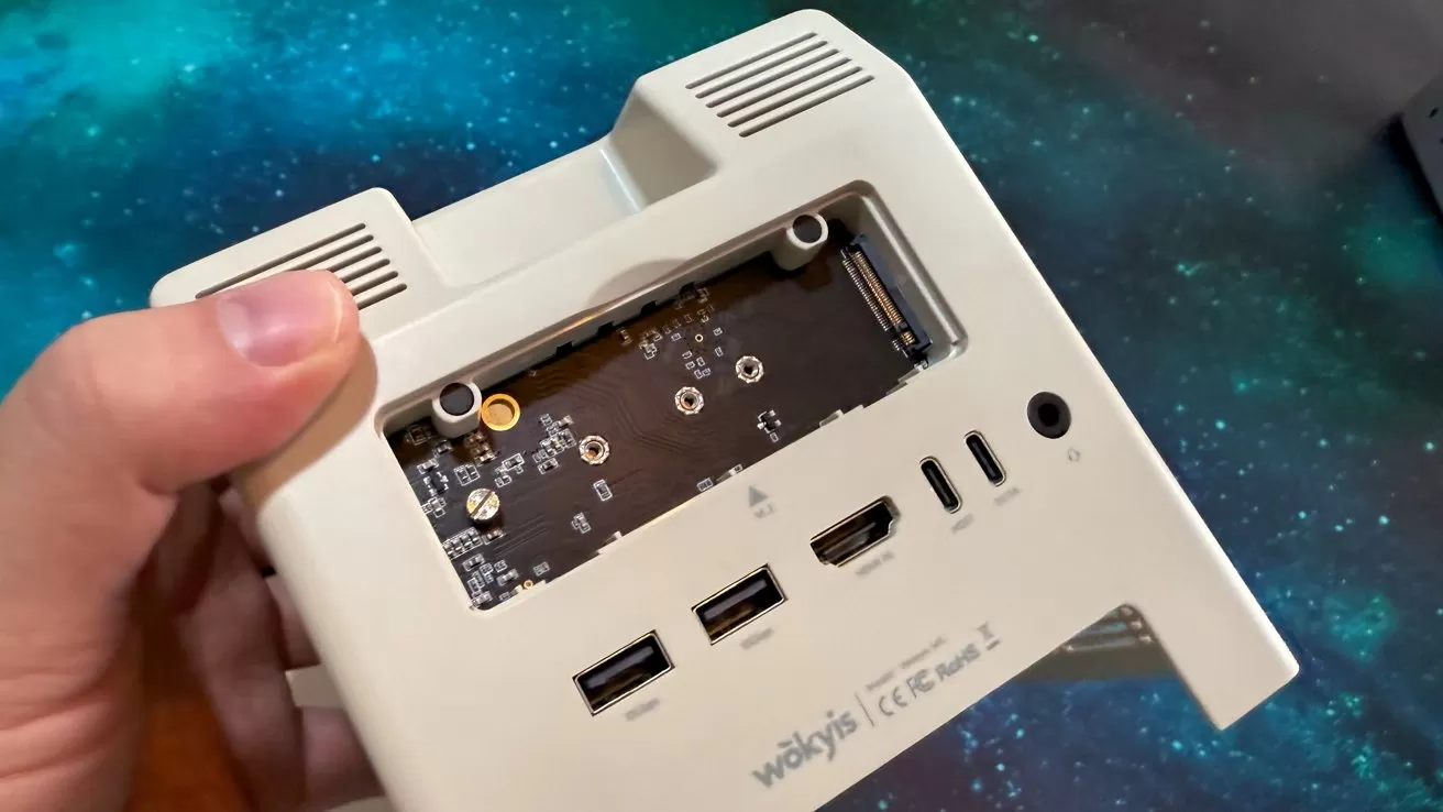 Hand holding a device with exposed circuit board and various ports, including USB and HDMI, against a starry background.